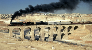 Slow train to Damascus with a black cloud coming out of the train running along.